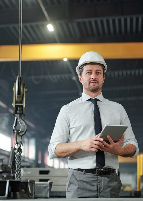 Geprüfter Industriemeister Metall plant Arbeitsabläufe digital mit Tablet in der Produktionshalle