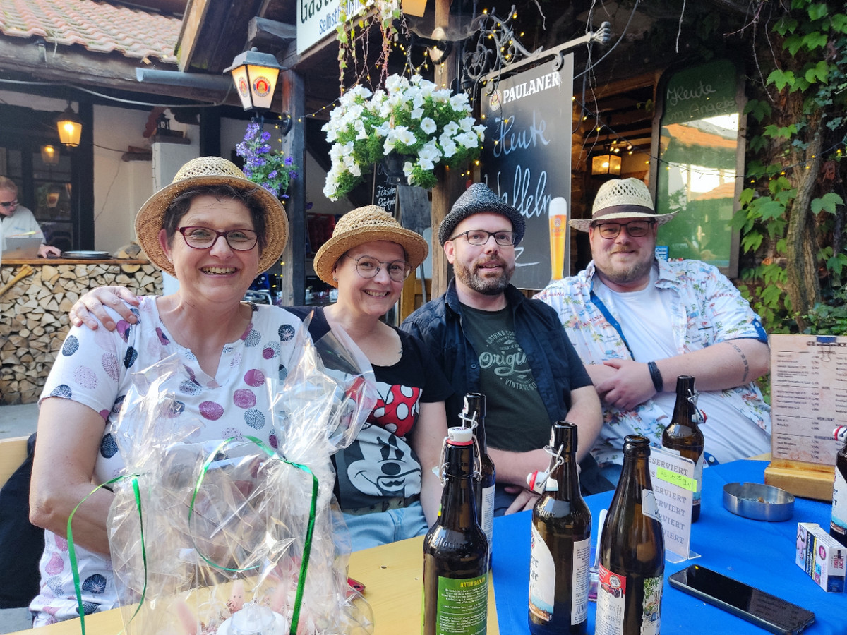 Vier Mitarbeitende von manQ sitzen im Biergarten des Hofgutes