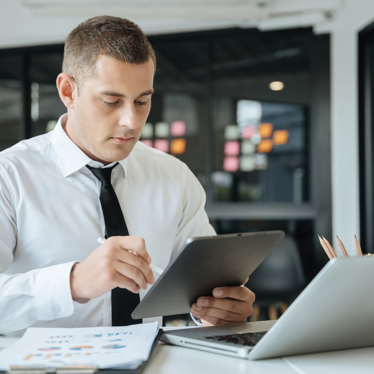 Geprüfter Fachwirt für Einkauf sitzt mit Tablet am PC
