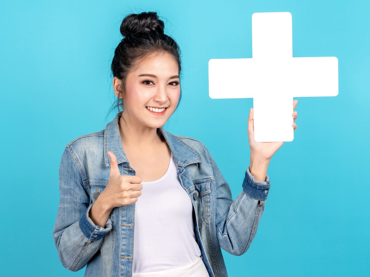 zufriedene Teilnehmerin hält großes Pluszeichen