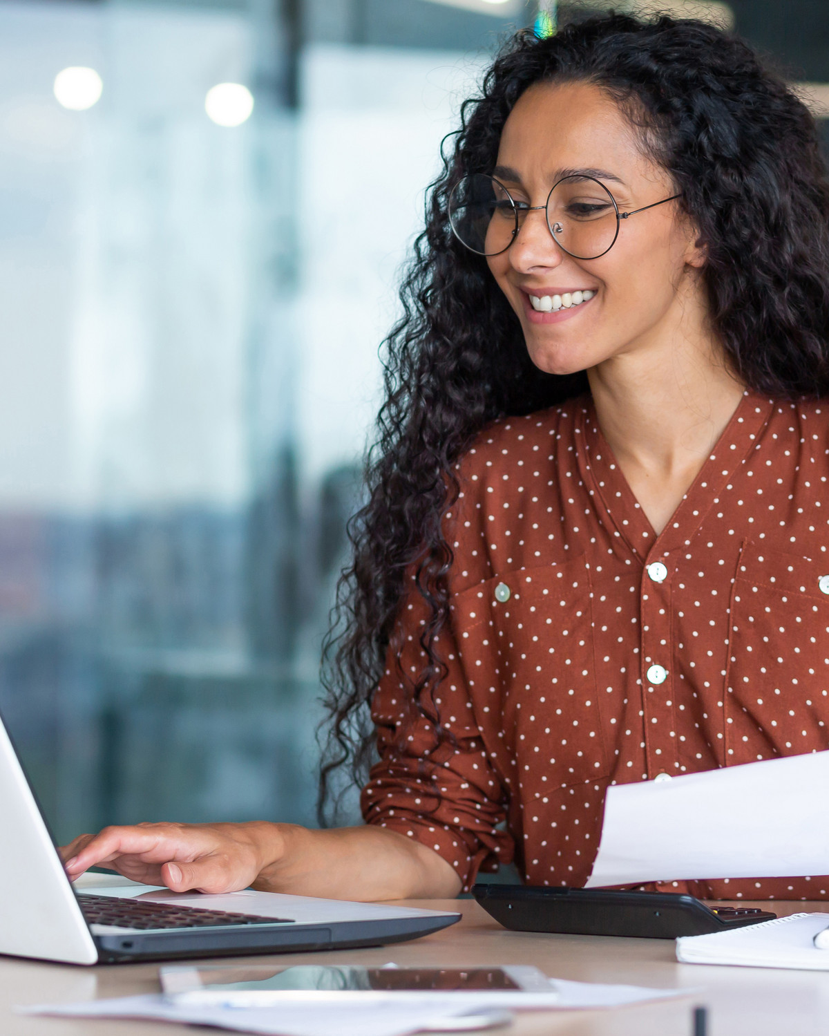 Betriebswirtin sitzt vor Laptop mit Ausdruck in der Hand