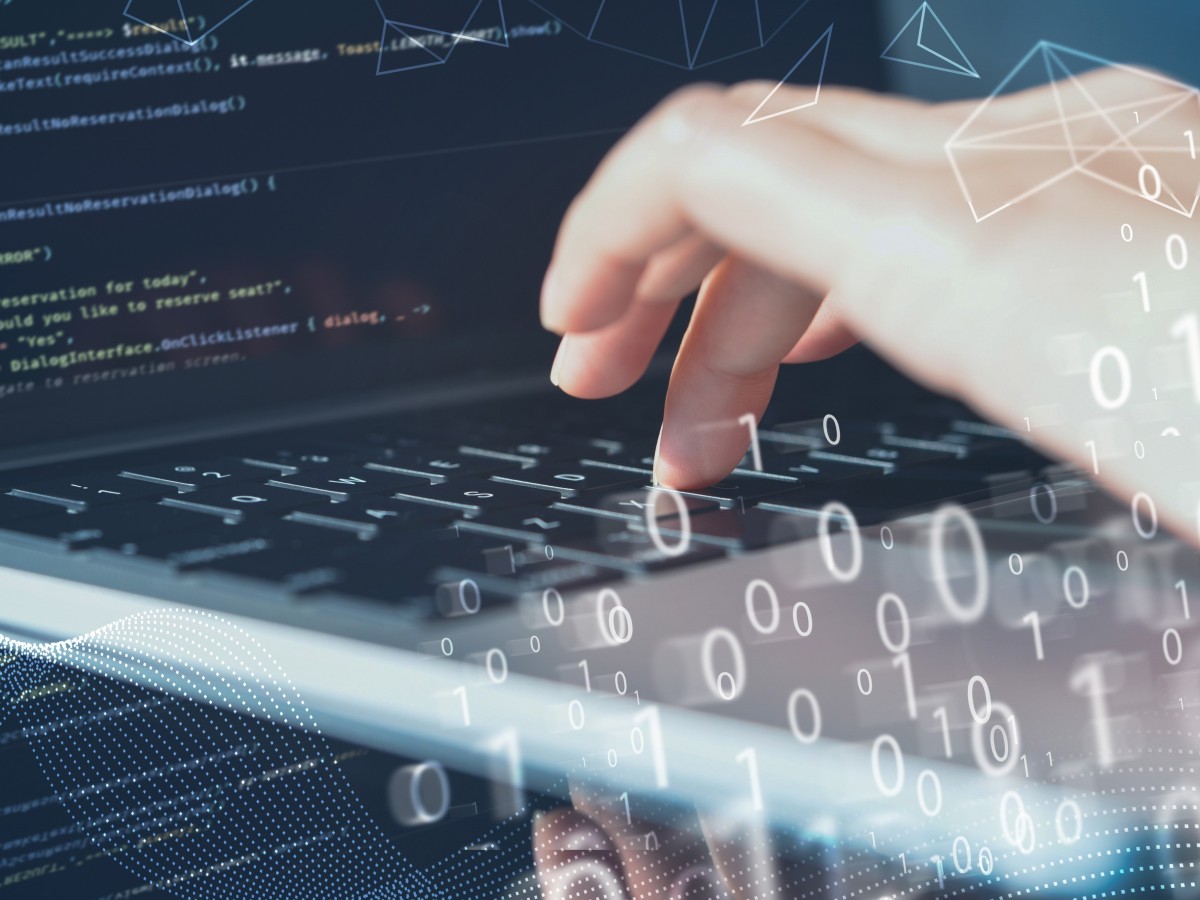 Hand gibt über Tastatur Daten ein, Nullen und Einsen erscheinen