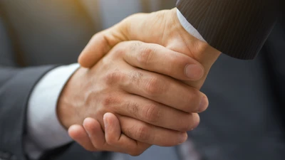 Unternehmensreferenzen von manQ Nahaufnahme Handschlag: manQ als Partner für Mitarbeiterentwicklung