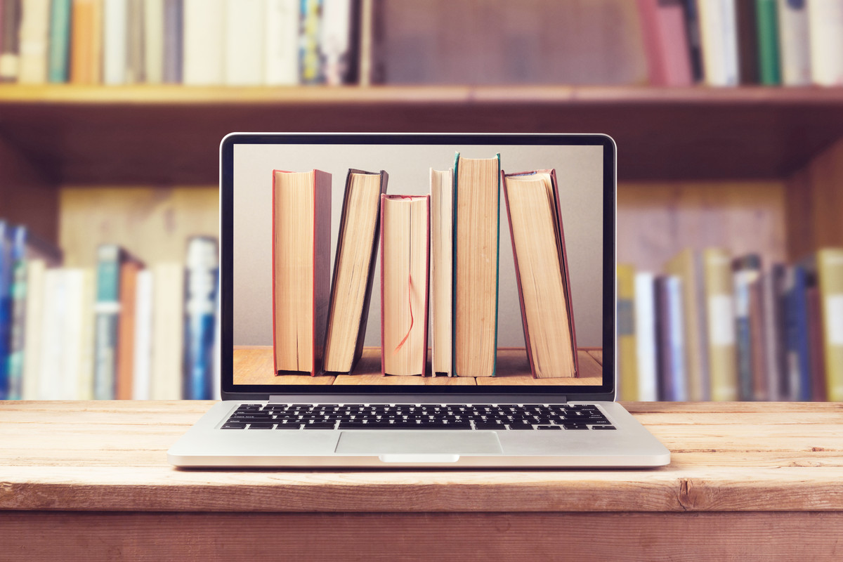 aufgeschlagener Laptop mit Bücherreihe